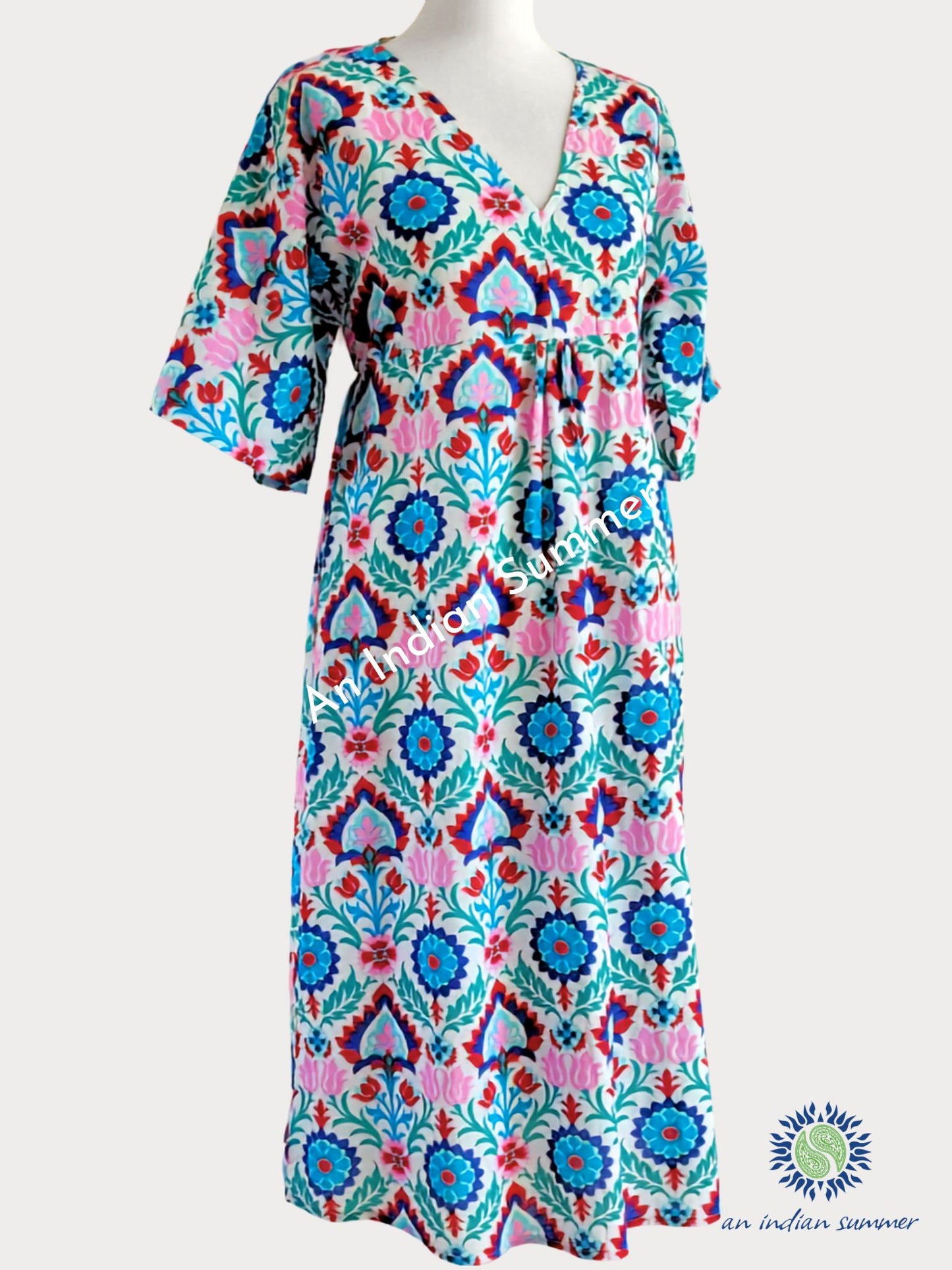 A multicolour Suzani Print printed cotton kaftan dress with a pink, turquoise, blue, and green geometric and floral pattern. An Indian Summer Samara Cotton Dress Turquoise & Pink Comfortable Easy-fit House Dress Ideal for Lounging or on the beach | Elasticated back | One Size | Cotton Voile | Handcrafted